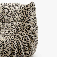 A close-up of the Togo Fireside Chair, Tablu by Ligne Roset, showcasing its plush, textured upholstery with a beige background and black leopard print pattern, featuring signature soft, gathered folds and the rounded, cozy silhouette inspired by the iconic Togo lounge chair.