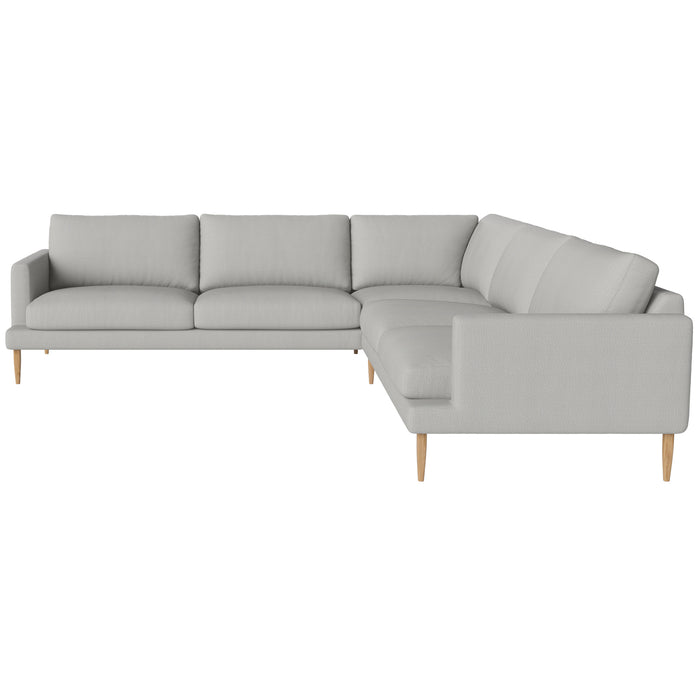 The Veneda 6 Seater Corner Sofa by Bolia features a modern L-shaped design in light gray with wooden legs and plush cushions, ideal for contemporary living spaces. Shown from an angle displaying both the front and side.