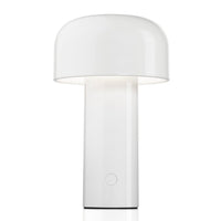 The Flos Bellhop Portable Lamp, IP54, is a modern, cordless white table lamp with a cylindrical base and dome-shaped shade, featuring an easy-to-use circular button near the bottom for control.